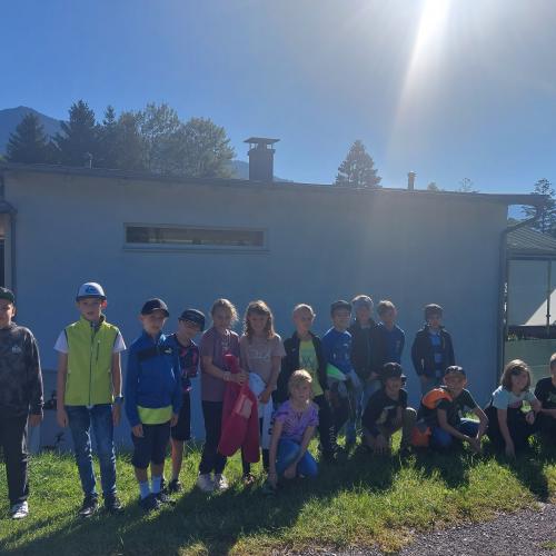 Kinder stehen in der Wiese vor einem Haus